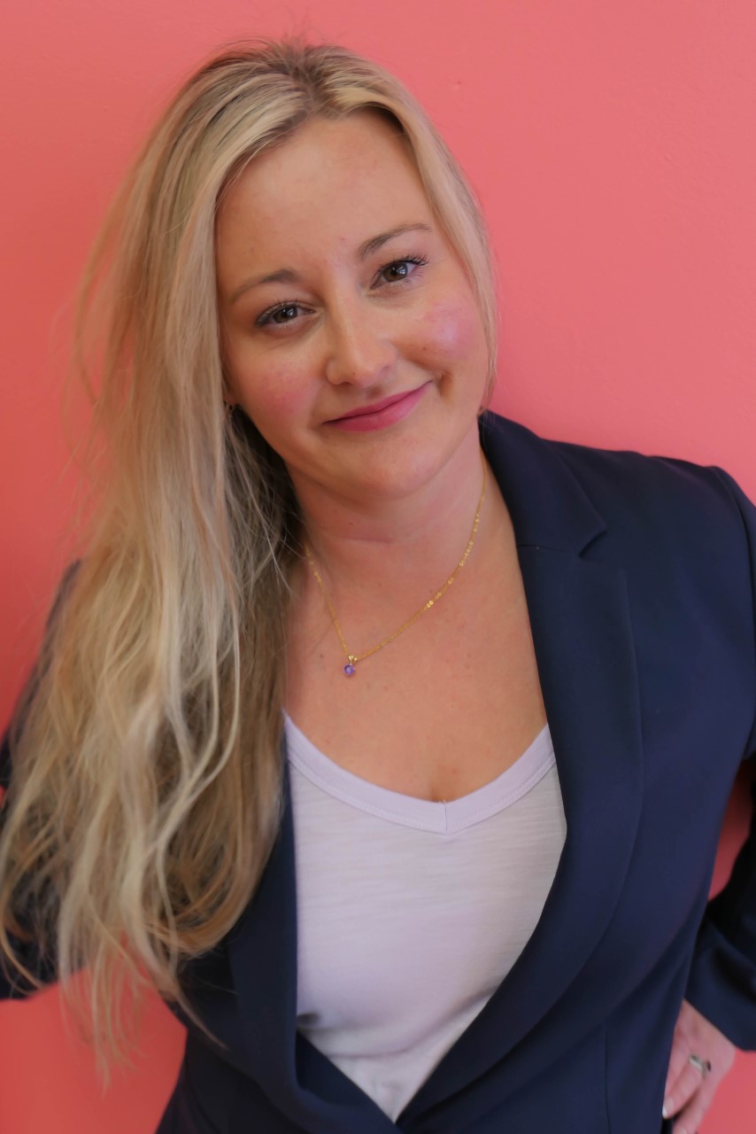 Kelly Notter-Antes standing in front of a pink backdrop.